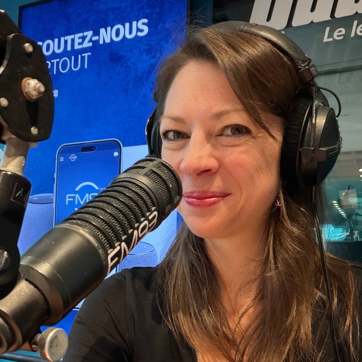 Portrait d'Andréanne Martin souriante et professionnelle dans un studio de radio moderne, assise devant un microphone de diffusion et portant un casque audio. Cette image illustre son expertise de chroniqueuse média depuis plus de 15 ans, collaborant avec des stations comme Rouge FM, FM93 et QUB radio.