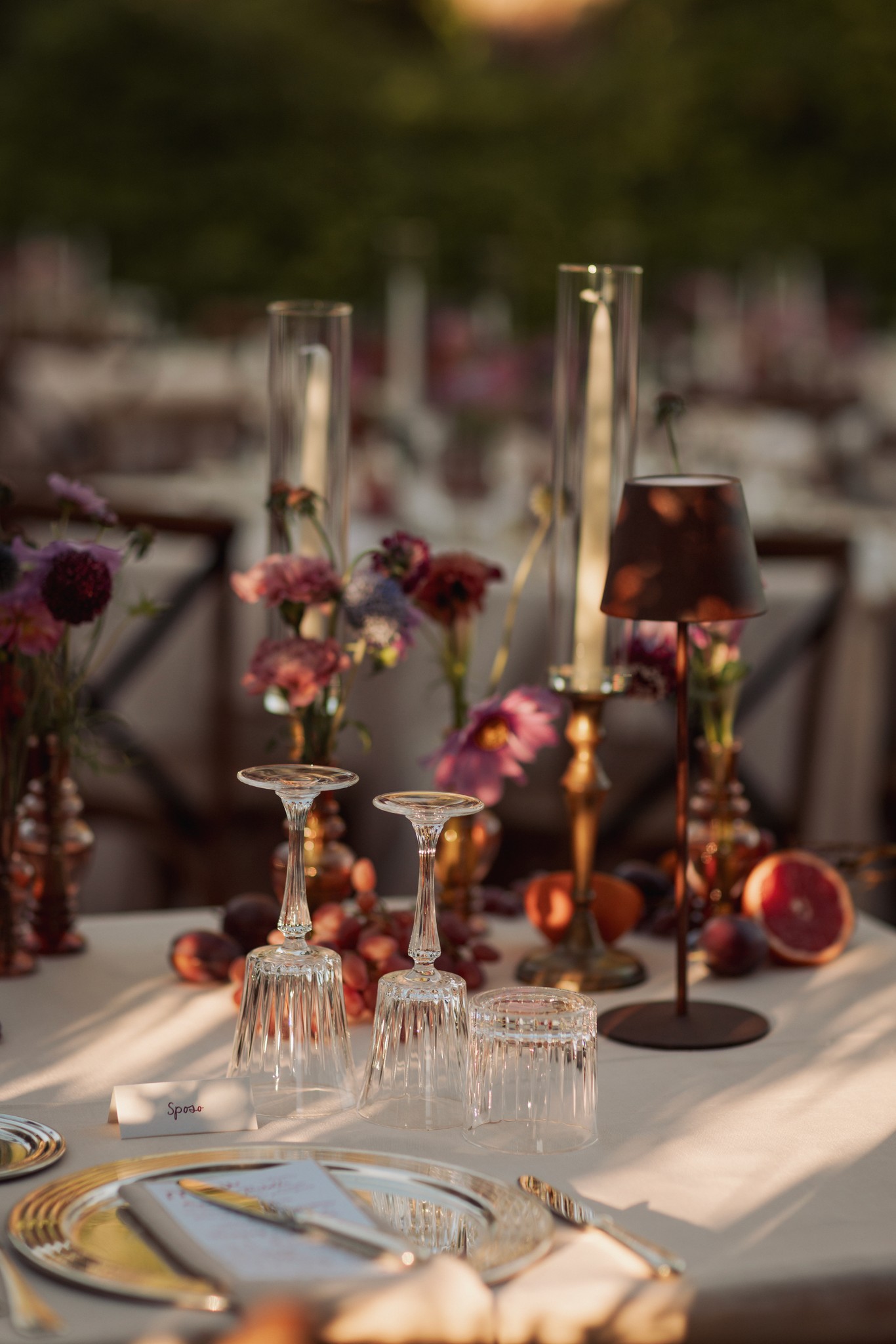 Tavolo ricevimento con calici, fiori borgogna e oro, candele accese, dettagli matrimonio al Castello di Scipione
