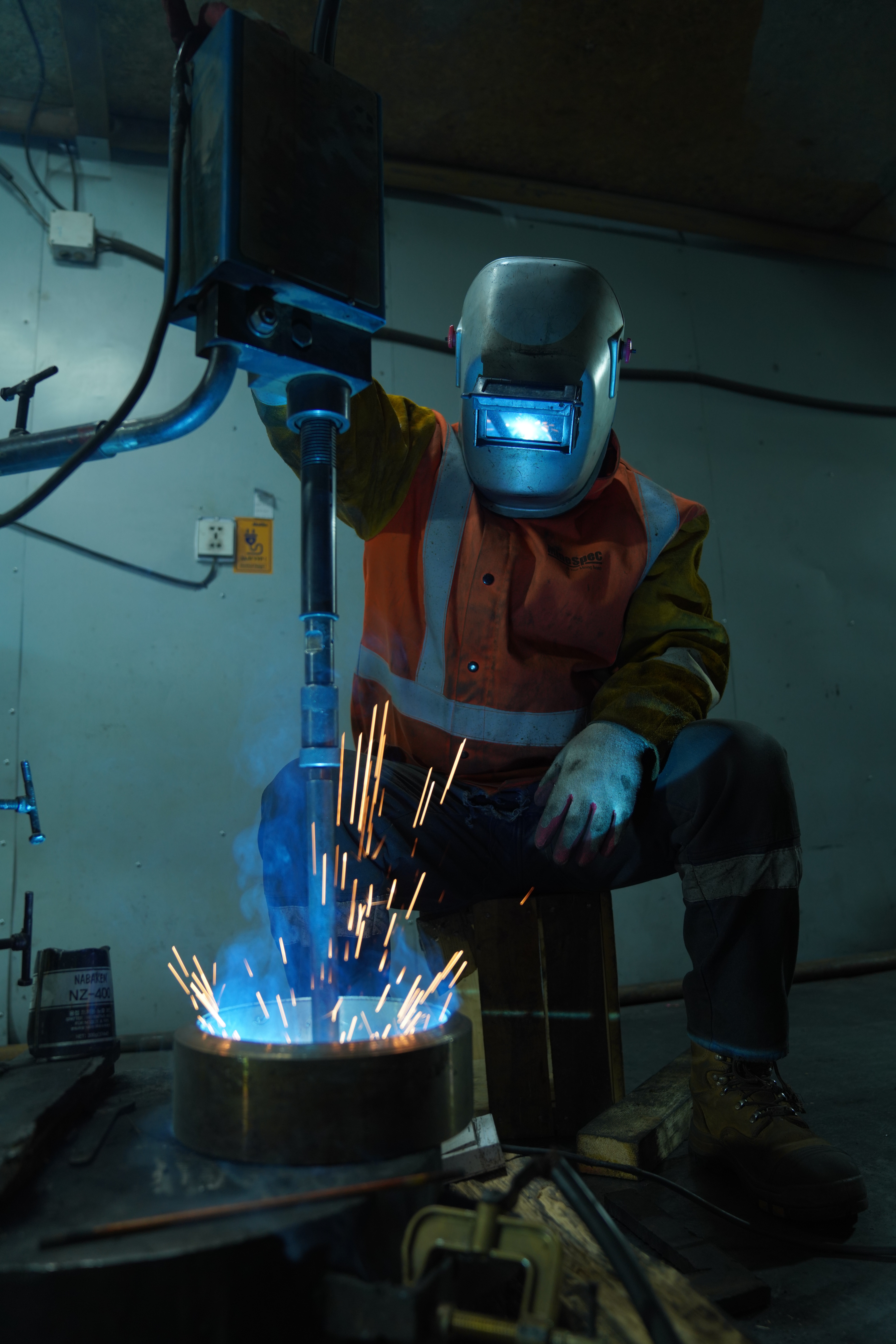 Male engineer in orange uniform and helmet standing with arms crossed          Ask ChatGPT