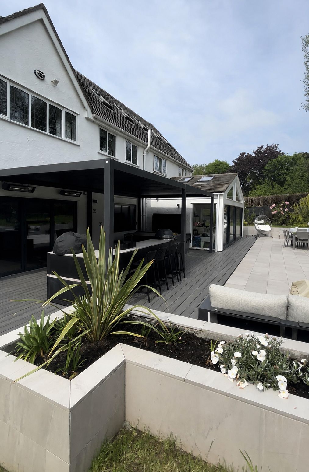 Contemporary Caldy garden with aluminium pergola, Grillo outdoor kitchen, porcelain planters and composite decking