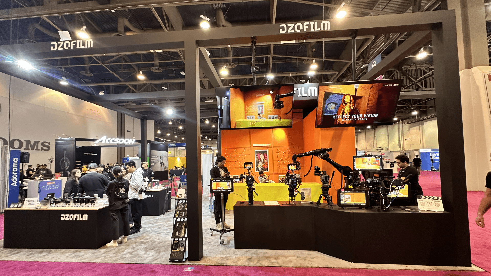 Front view of DZOFILM booth at NAB 2024, featuring a live shooting zone with cinema cameras and a vibrant orange backdrop.