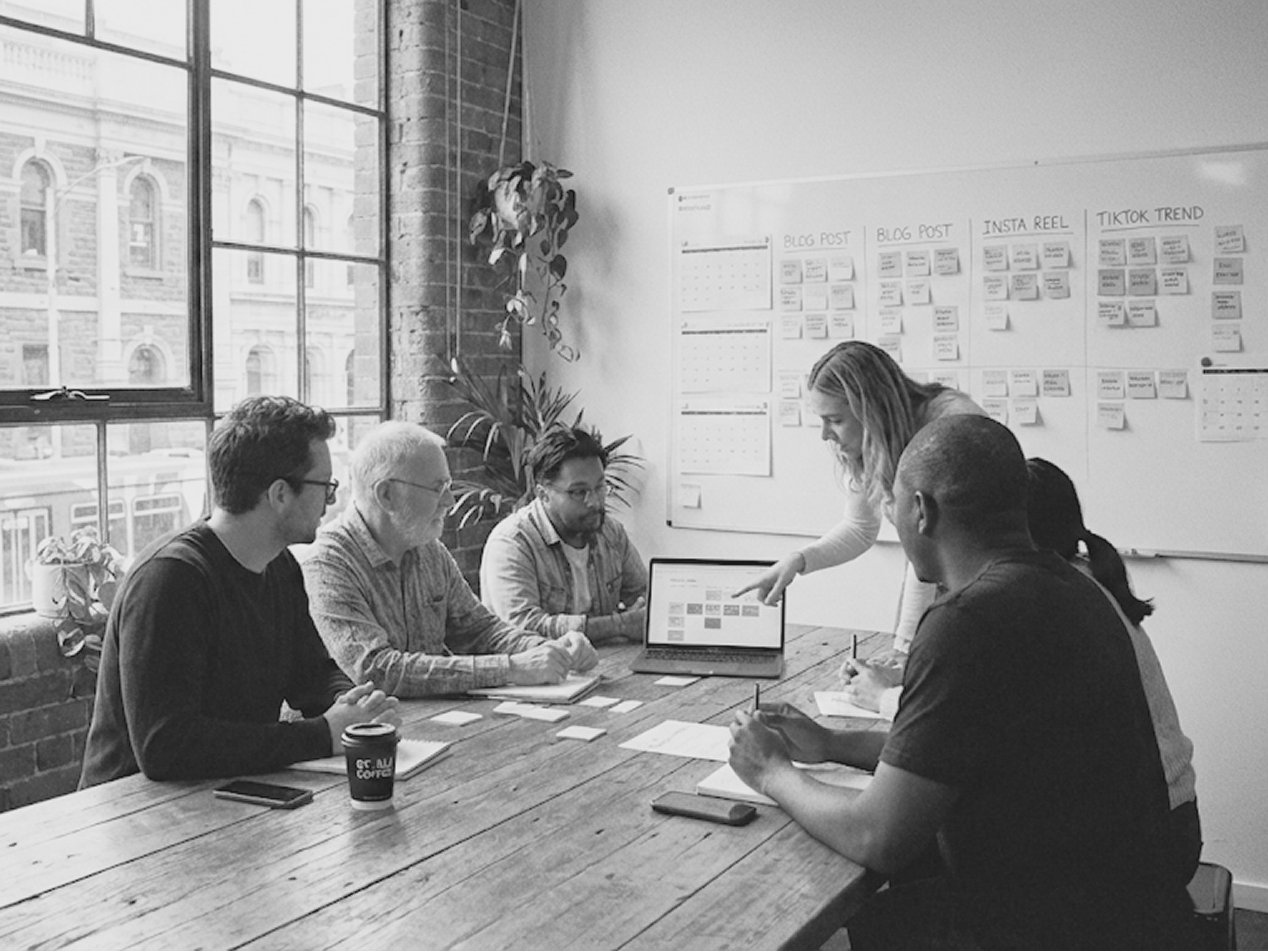 A marketing team around a conference table, planning a social media content calendar