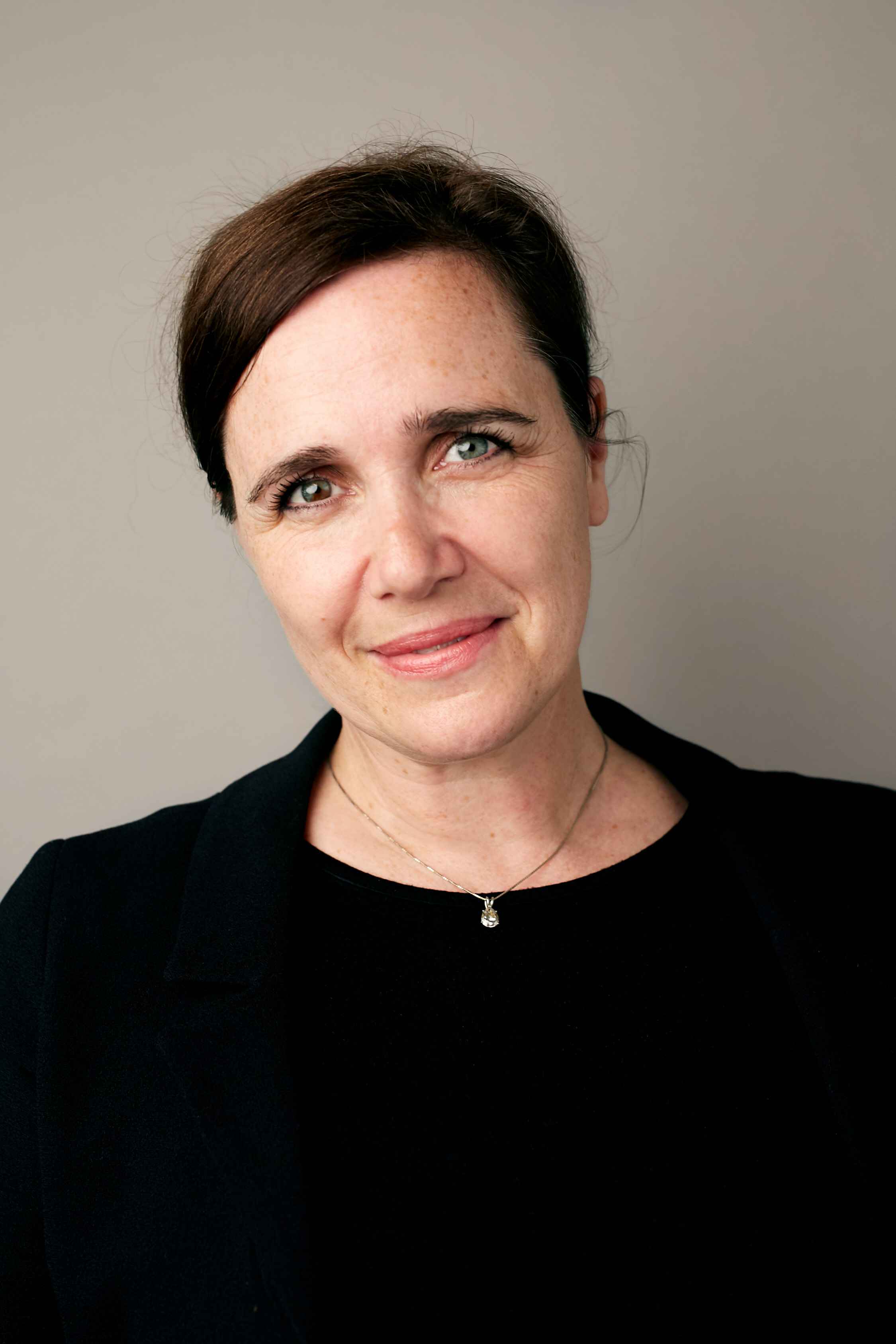 Woman with auburn hair and blue eyes smiles.