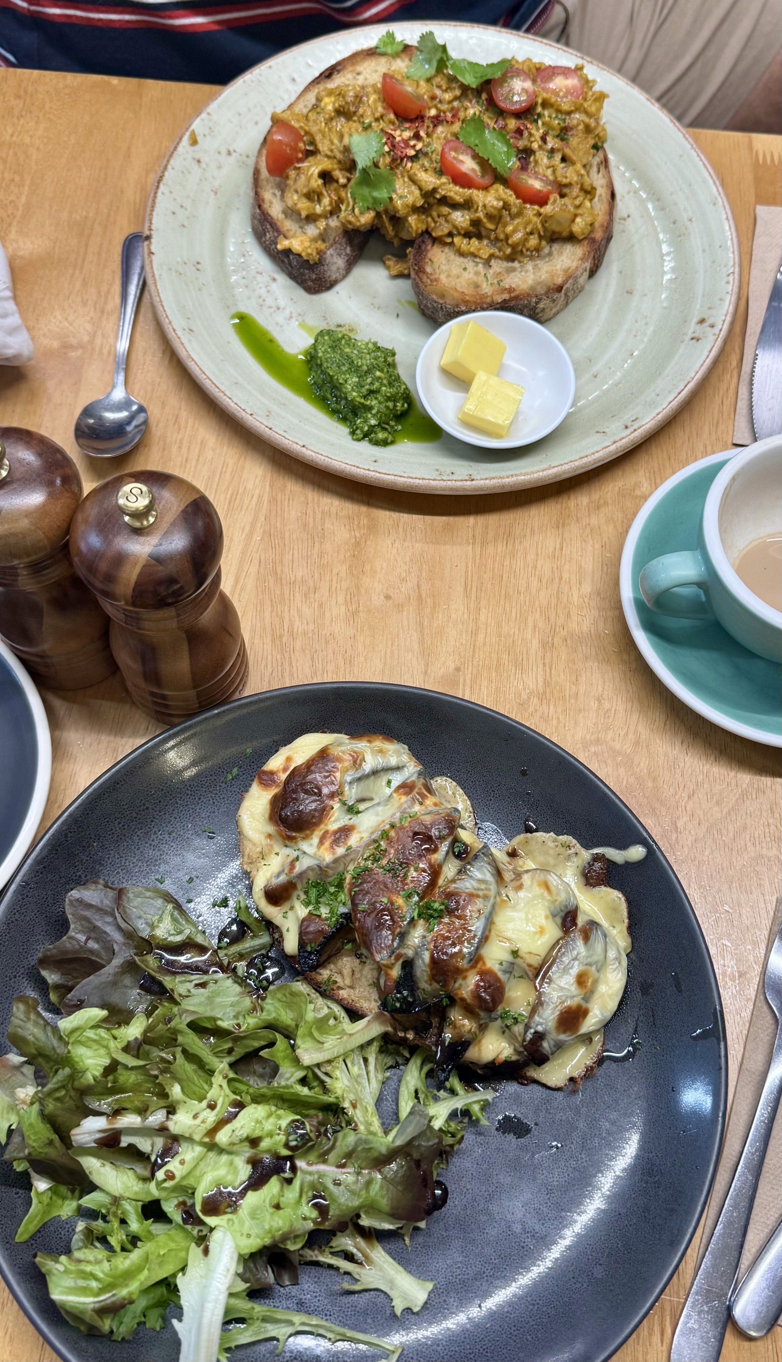 Sourdough with mushrooms and cheese with salad on one plate; sourdough with masala eggs on the other plate