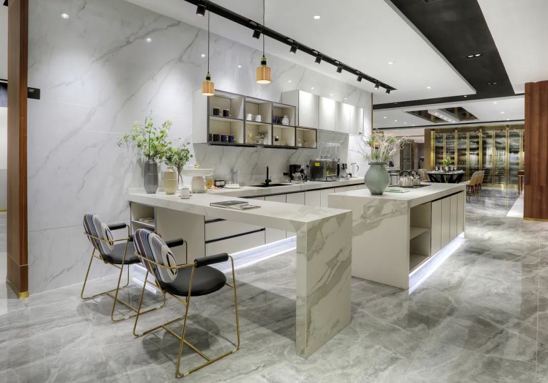 A modern kitchen with marble countertops, backsplash, and floor tiles, featuring an open-plan design. The marble’s light grey veining complements the sleek and sophisticated aesthetic.