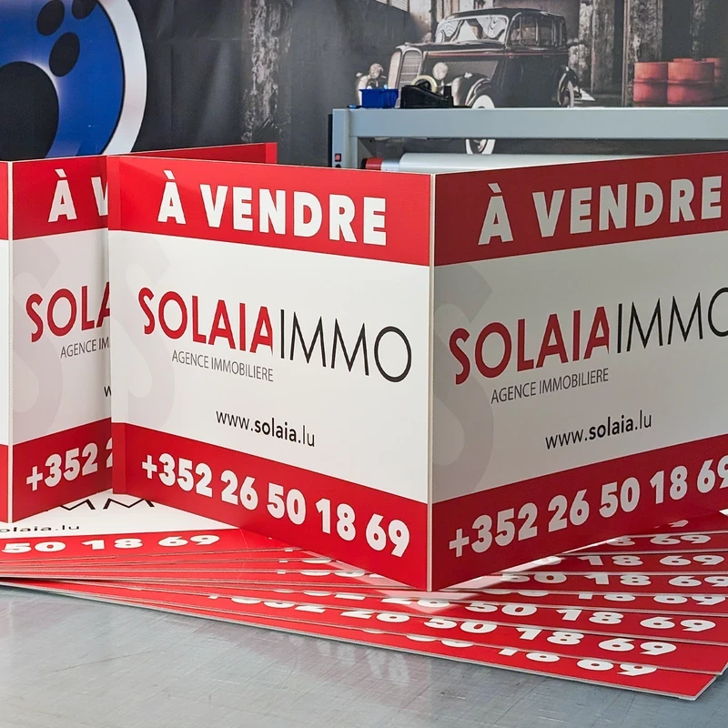 Red and white 'À VENDRE SOLAIA IMMO' estate signs