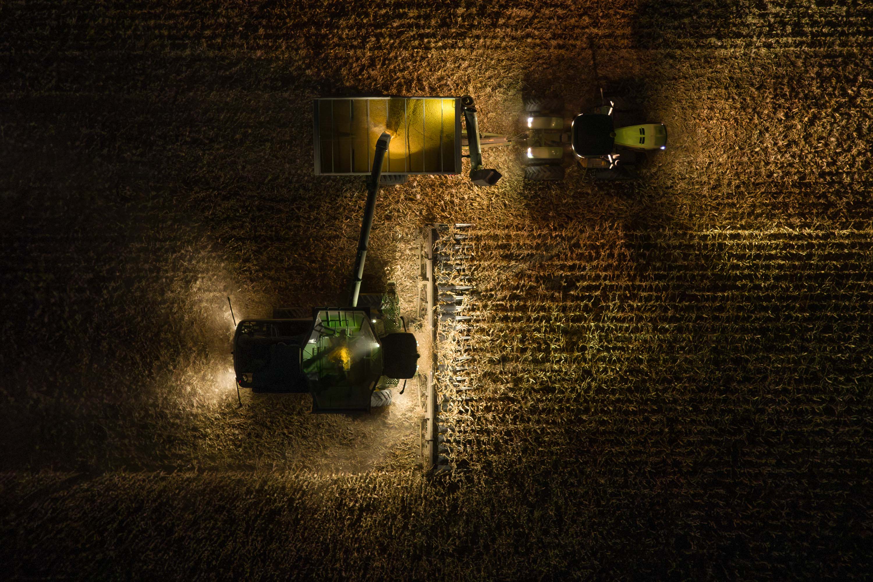 John Deere combine with John Deere Tracker during harvest from above at night