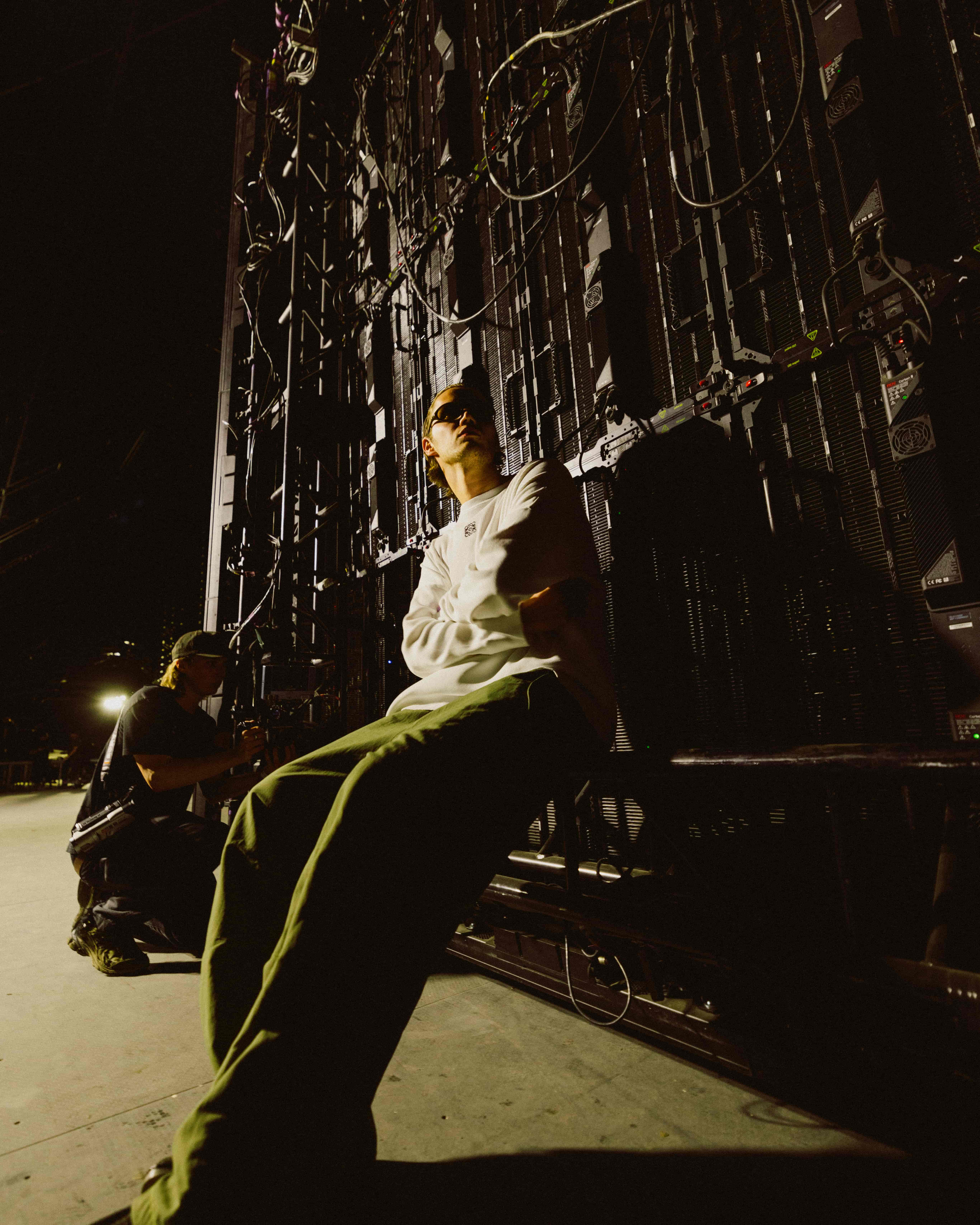 MAU P backstage at Coachella 2025 leaning against stage LED wall and production rigging, captured by A World Away creative director Brandon Densley