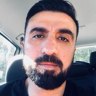 Mann med mørkt hår og skjegg inne i en bil