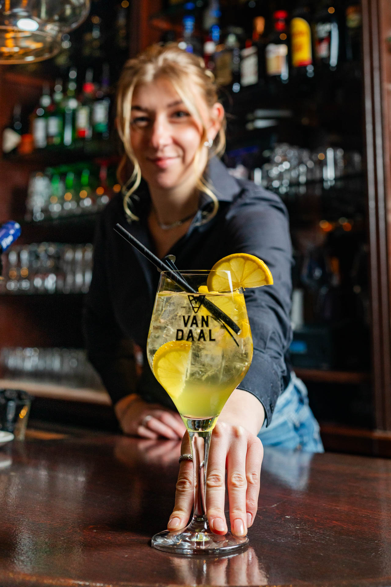 Een serveerster schuif een cocktailglas naar voren vanaf de toonbank achter de bar
