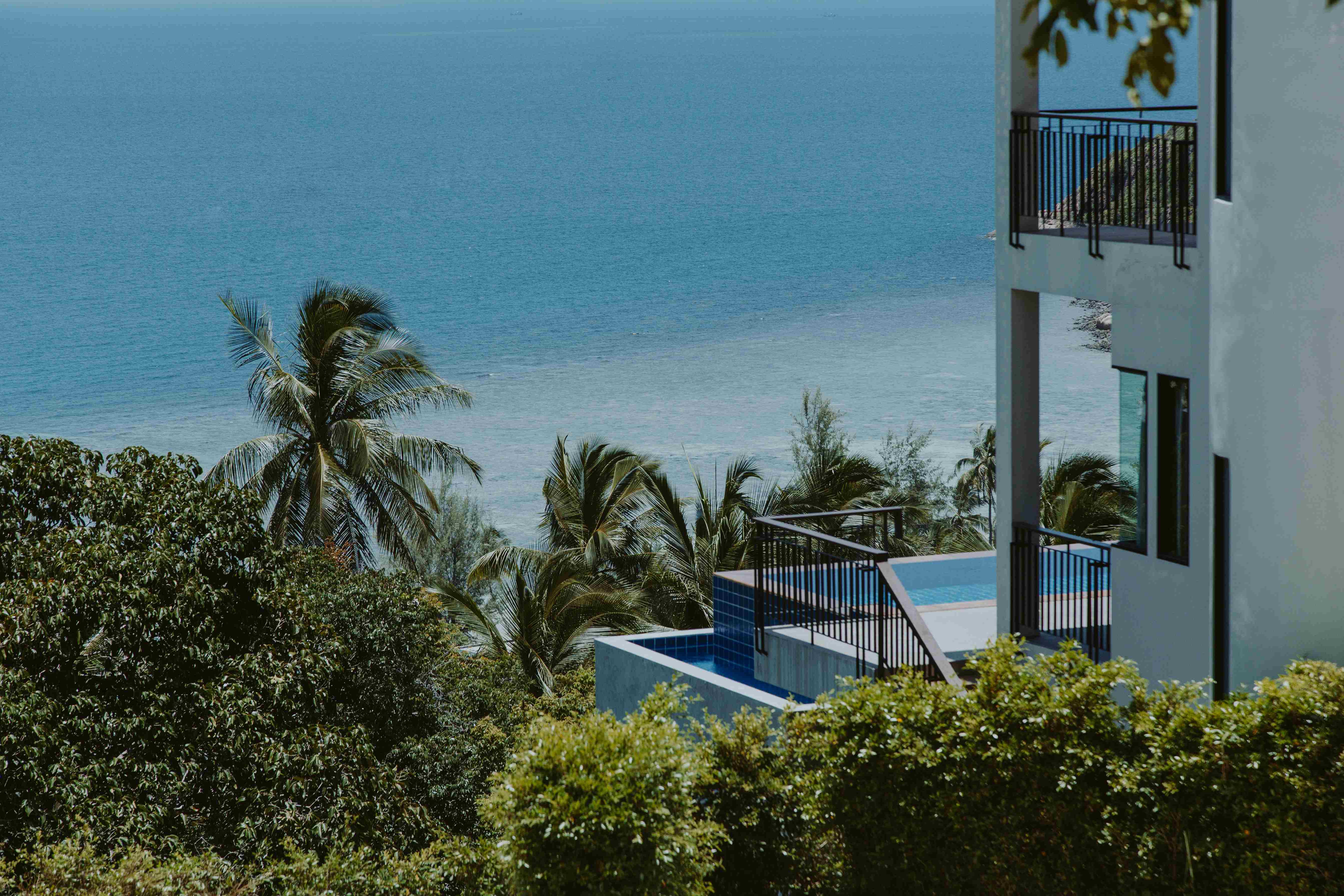 Modern coastal villa overlooking the sea with palm trees and a private pool in Turkey.