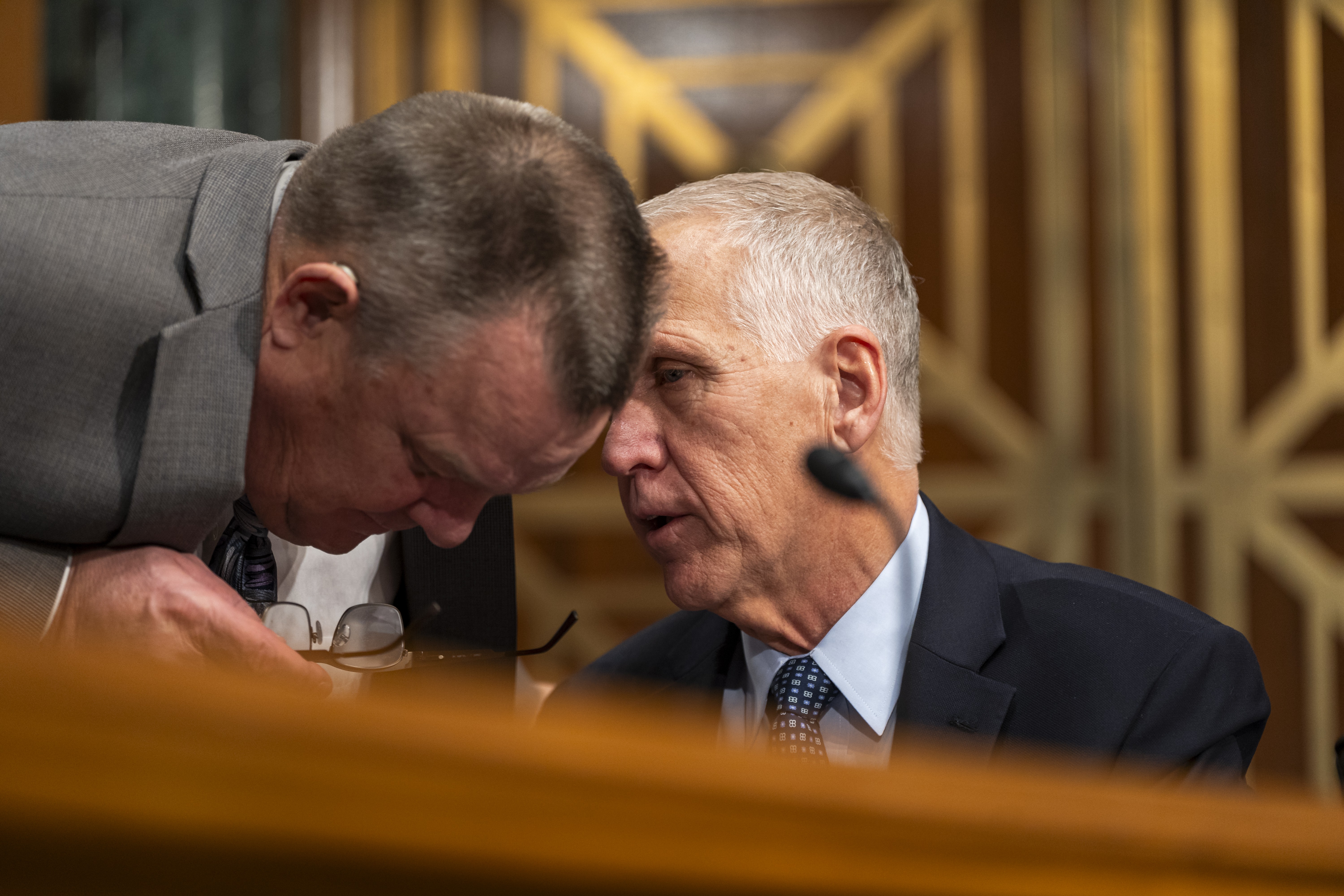 Sen. Thom Tillis (R-N.C.) converses with Sen. John Tester (D-Mont.) at a Senate Banking Committee hearing on January 18, 2024