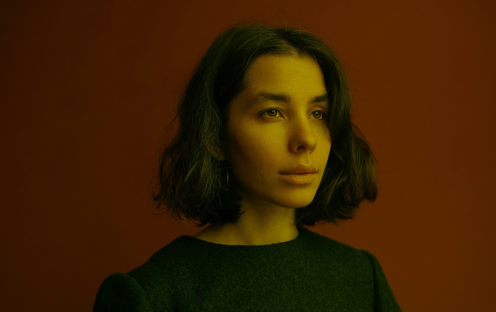 a woman with shoulder length hair standing in front of a red wall