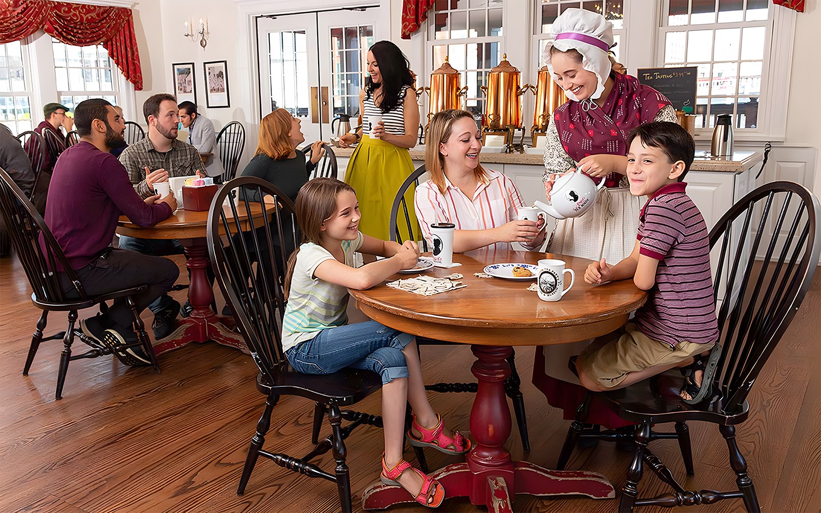 Tourists enjoying tea service at Abigail's Tea Room with a costumed server.