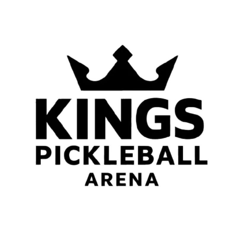 A man with wavy brown hair smiles slightly while wearing a black turtleneck and blazer. The background is softly blurred, suggesting a sunny outdoor setting.