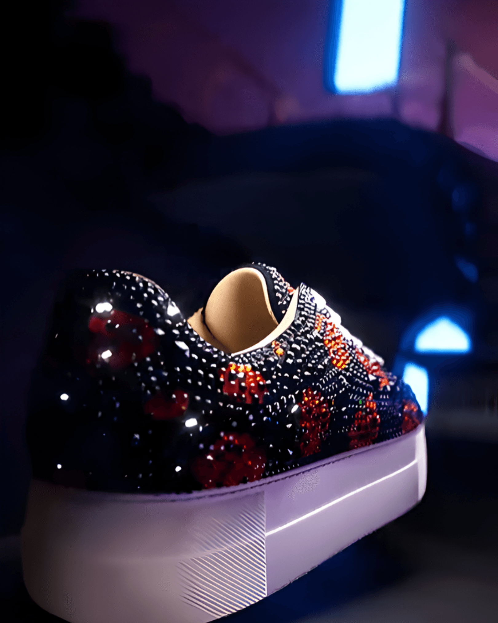 A close-up of a platform sneaker covered in sparkly black and orange crystals against a dark blue background