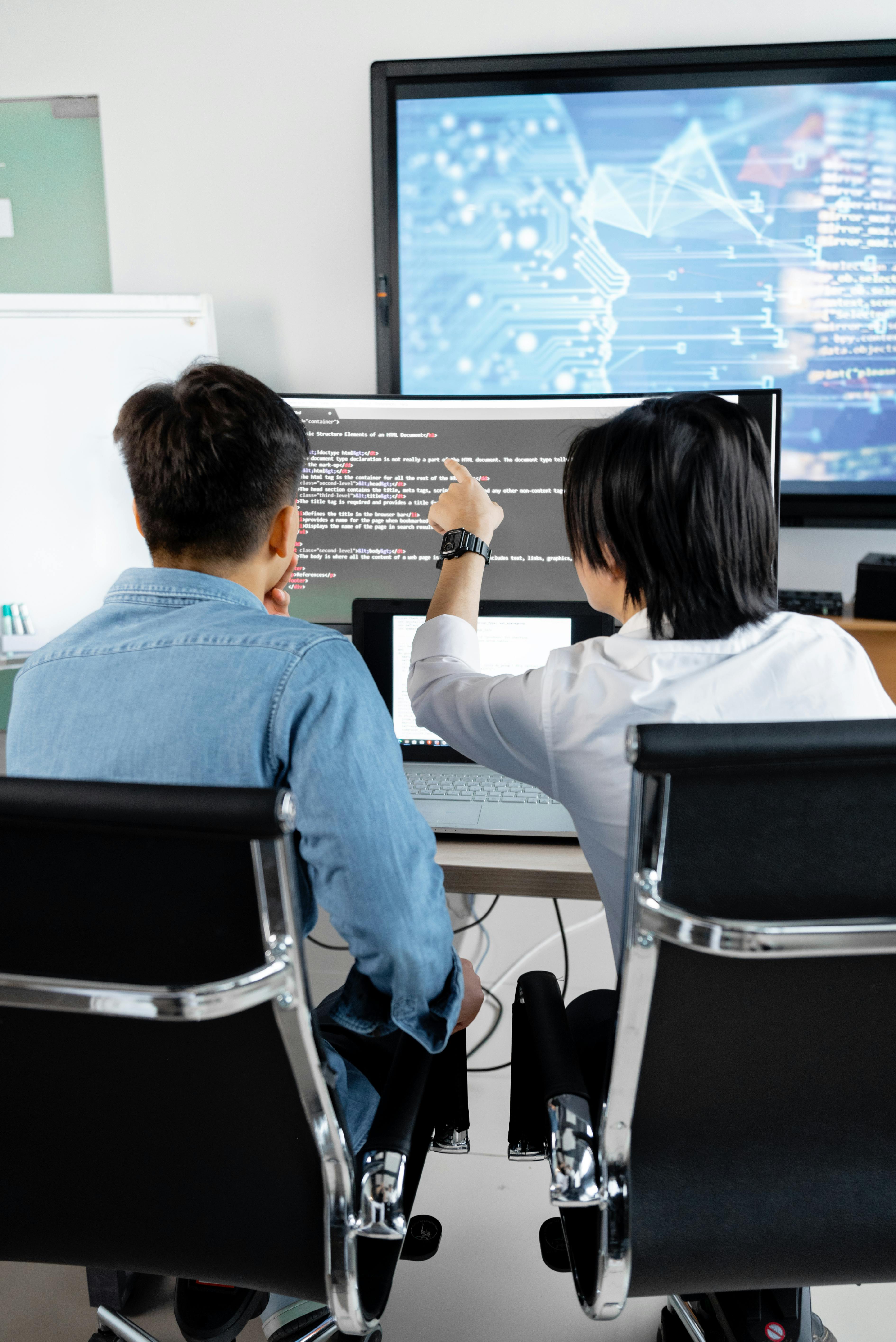 IT consultants reviewing and discussing code on a computer screen during a technical strategy session.