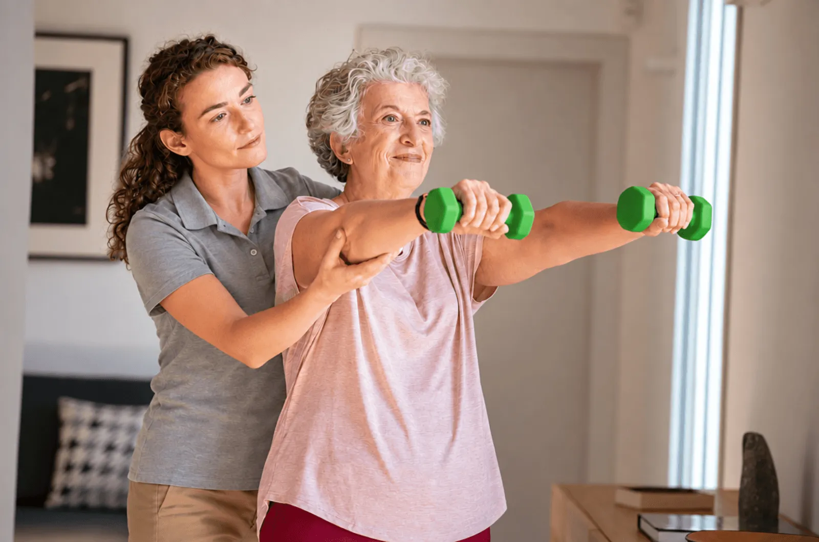 Physiotherapist helping an older woman exercise with hand weights