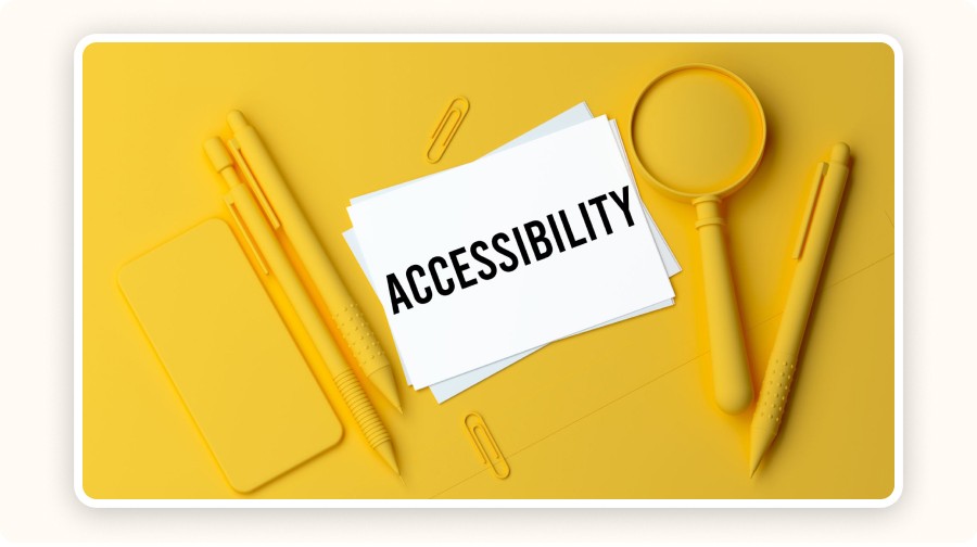 Carte avec le mot "Accessibility" posée sur un bureau jaune avec loupe et stylos