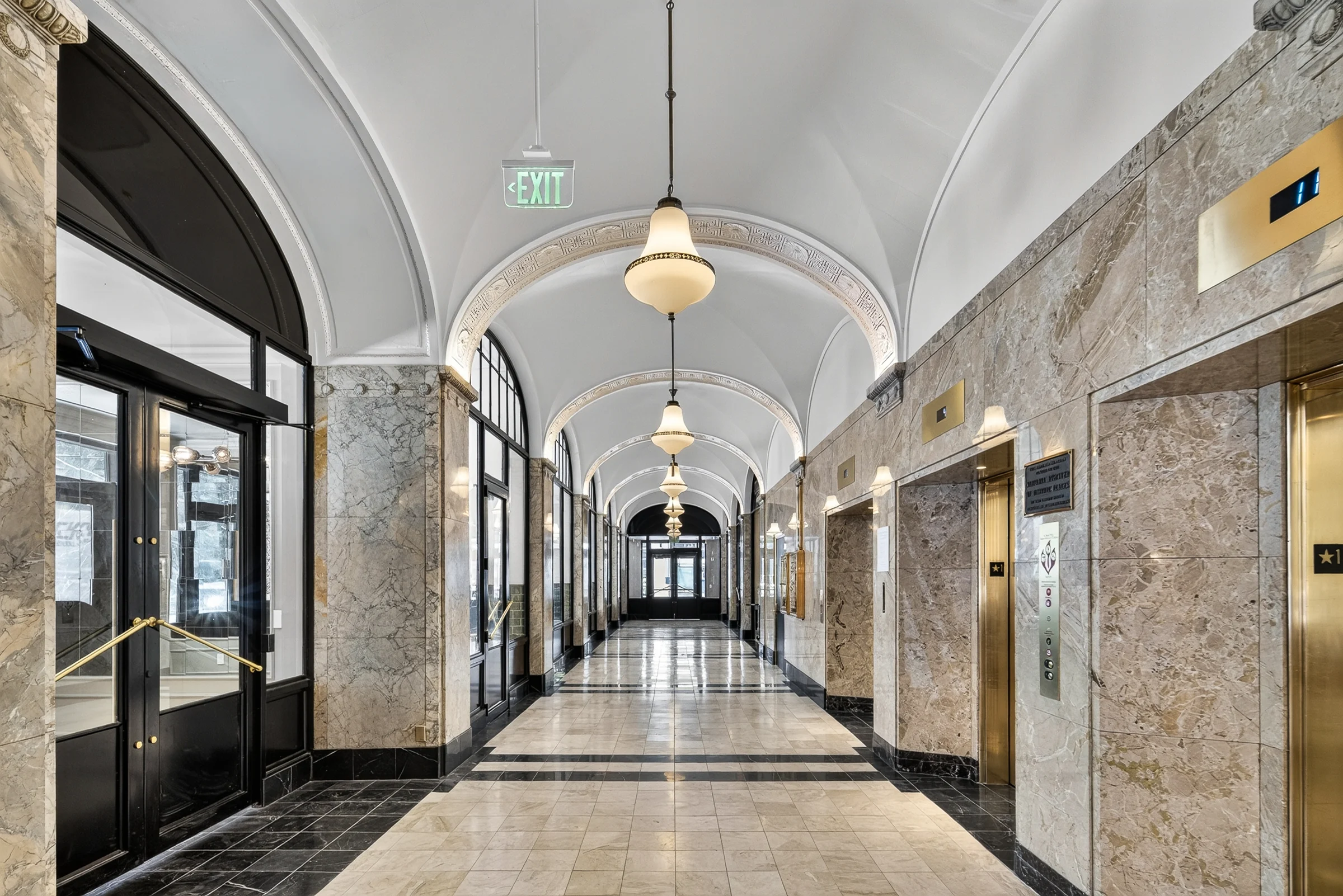 Long corridor at 210 E 6th with vaulted ceiling, arched windows and stone walls