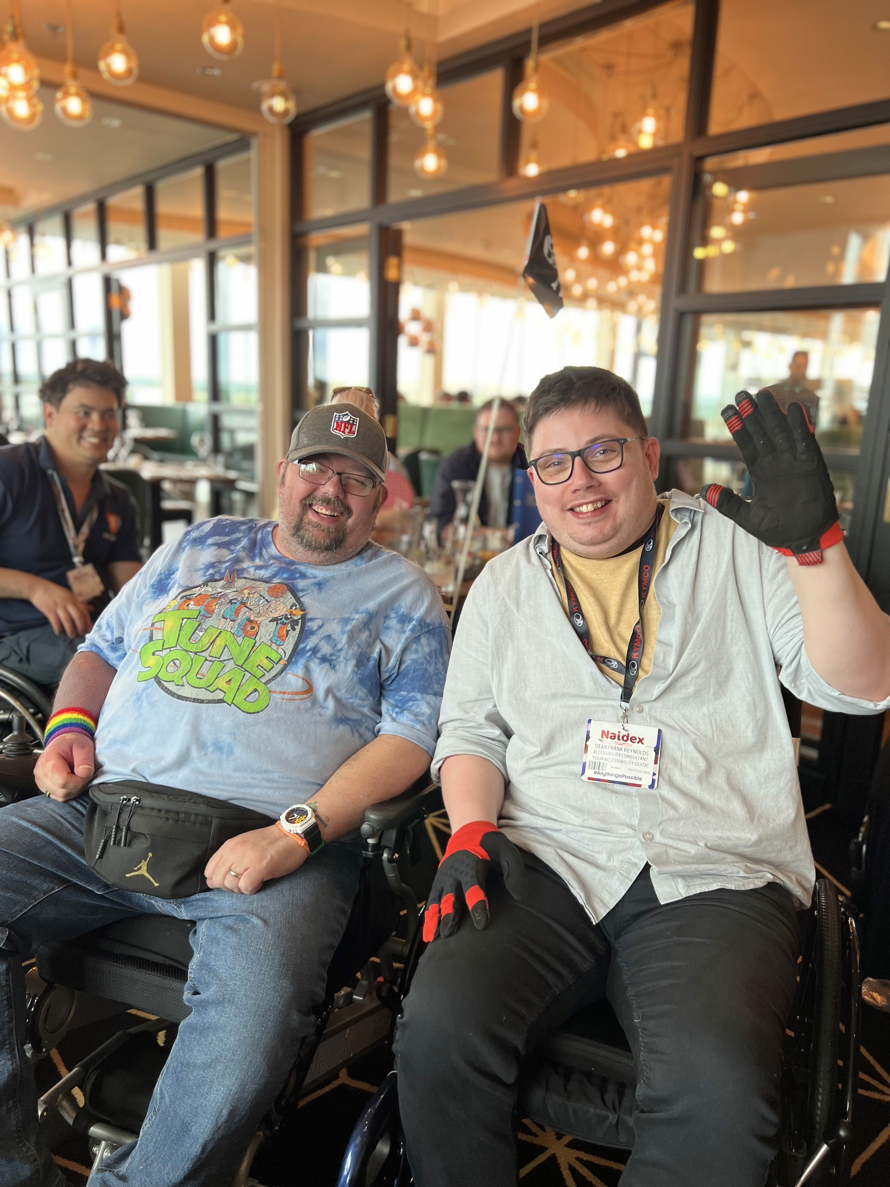 Two wheelchair users smiling in a restaurant.