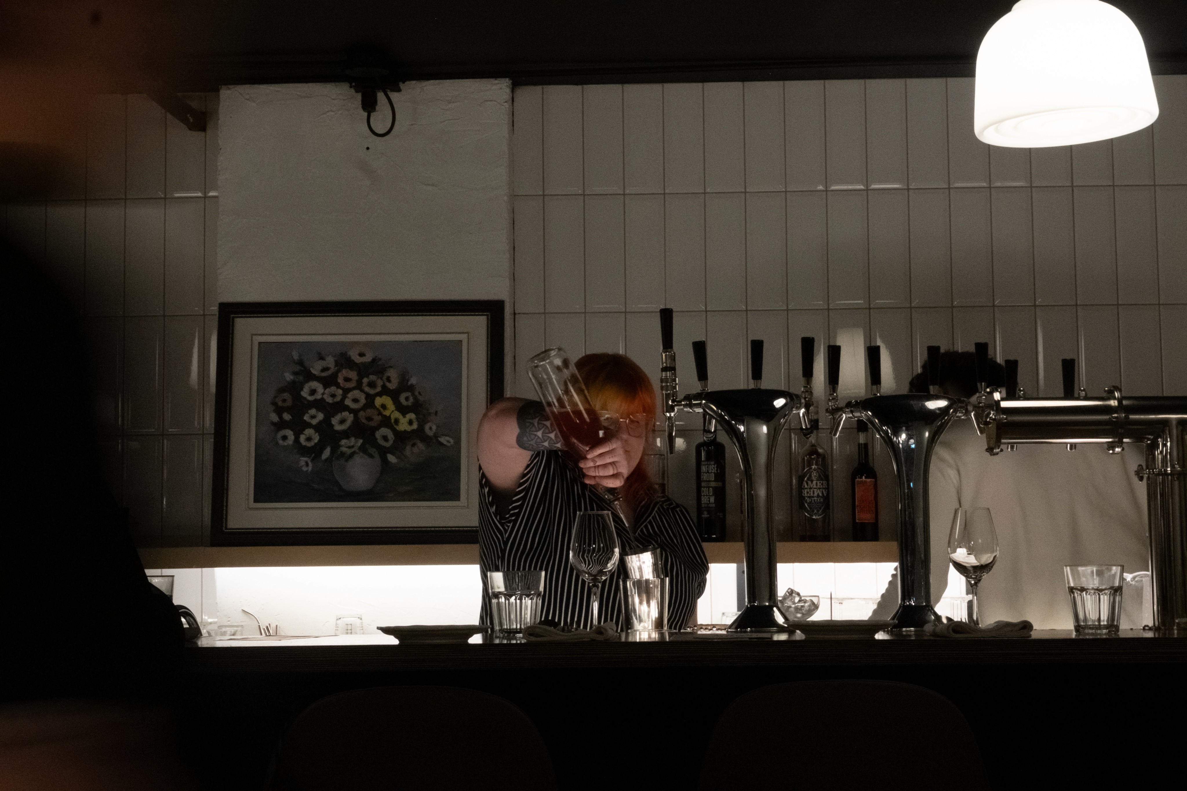 La barmaid du Saison prépare un cocktail derrière le bar.