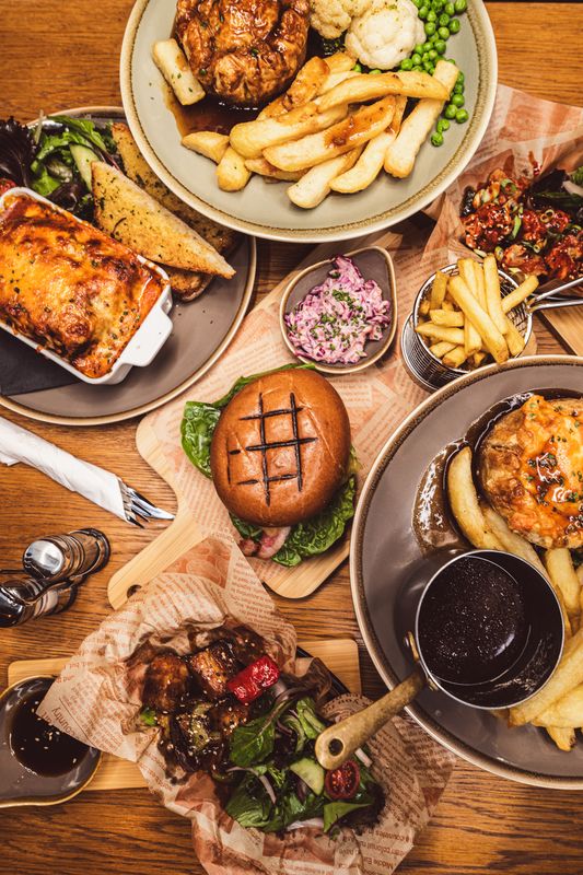 A selection of food on a table taken from above burger fries lasagne