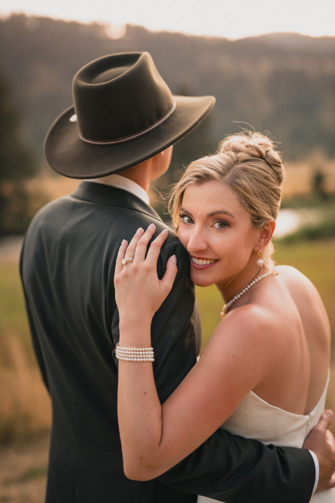 One newlywed looking toward the camera over their partner’s shoulder