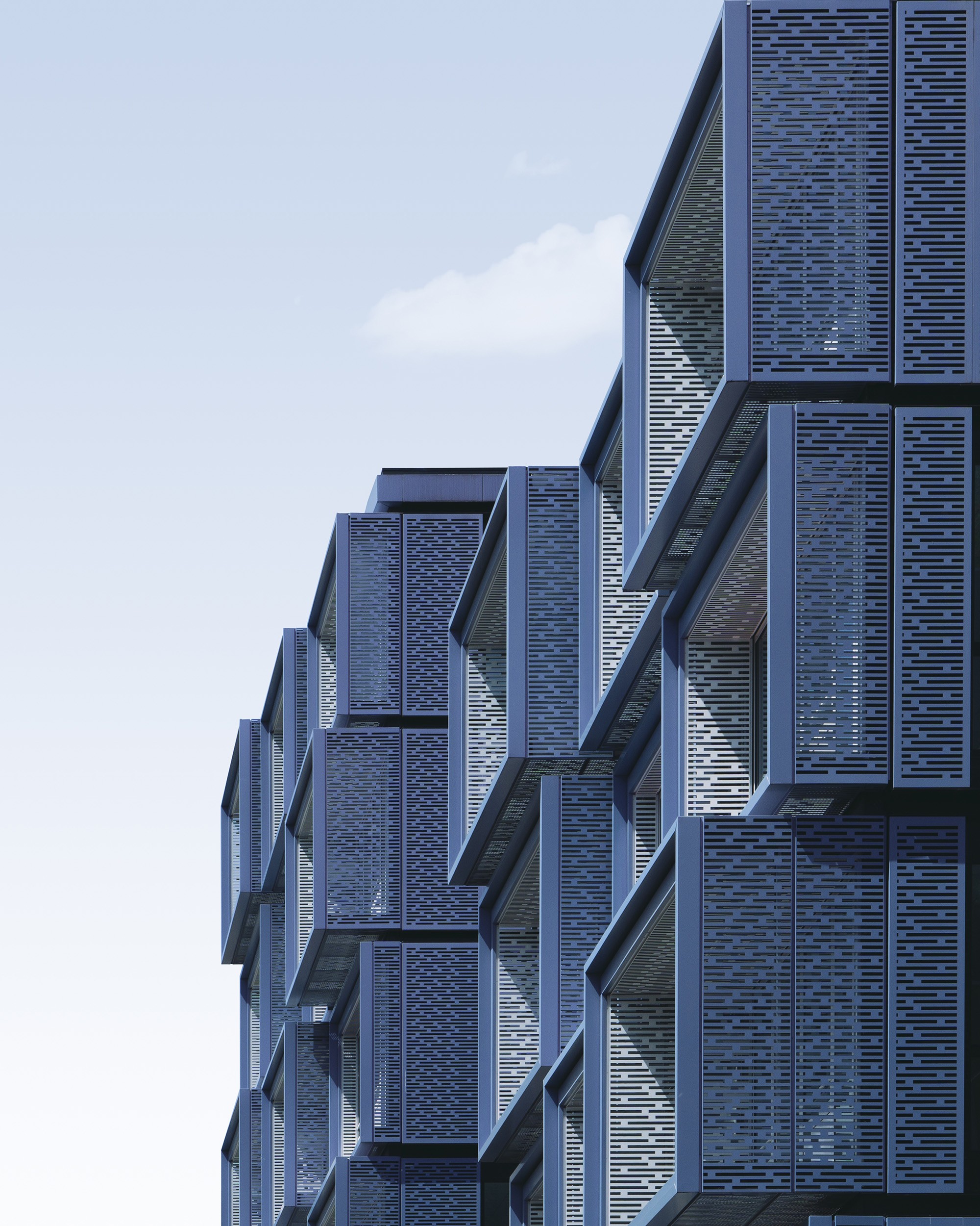 Modern blue metal cubical building facade against a clear sky