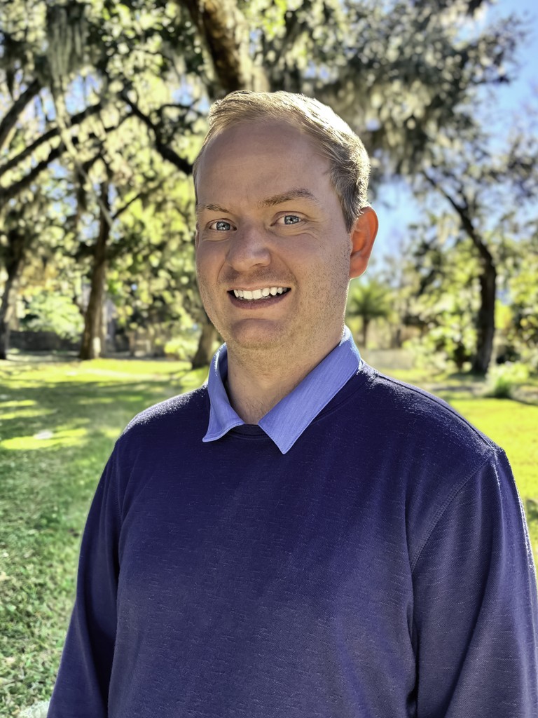 Portrait of a person in a pink sweater against a light background