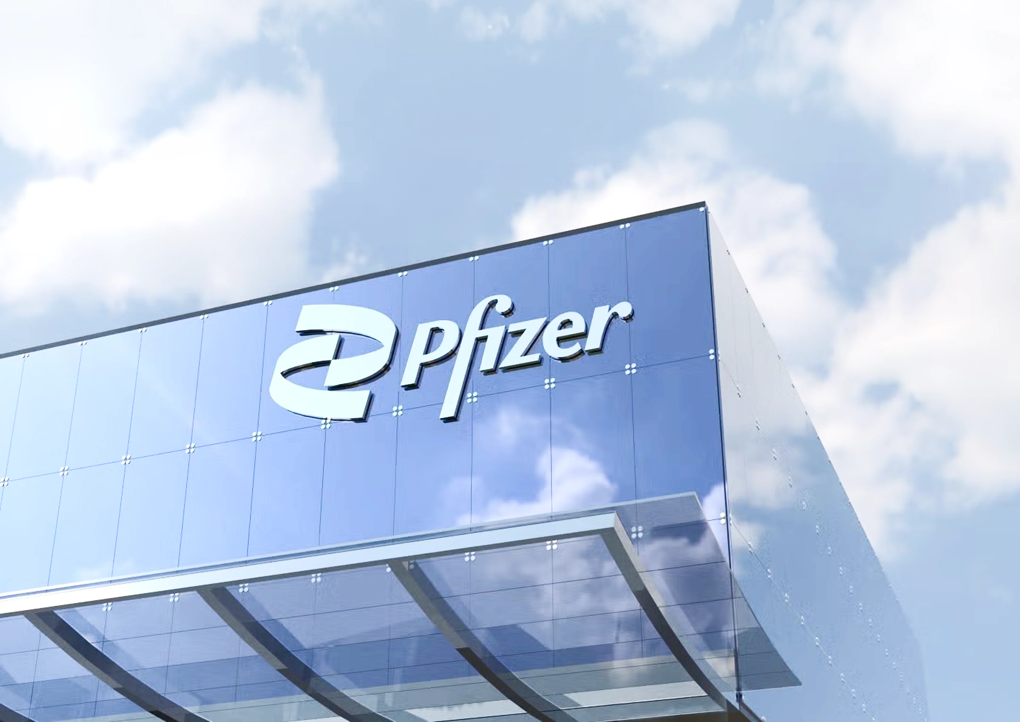 Upward angle shot of the corner of a glass office building with the Pfizer logo and a blue sky with clouds reflected in the facade