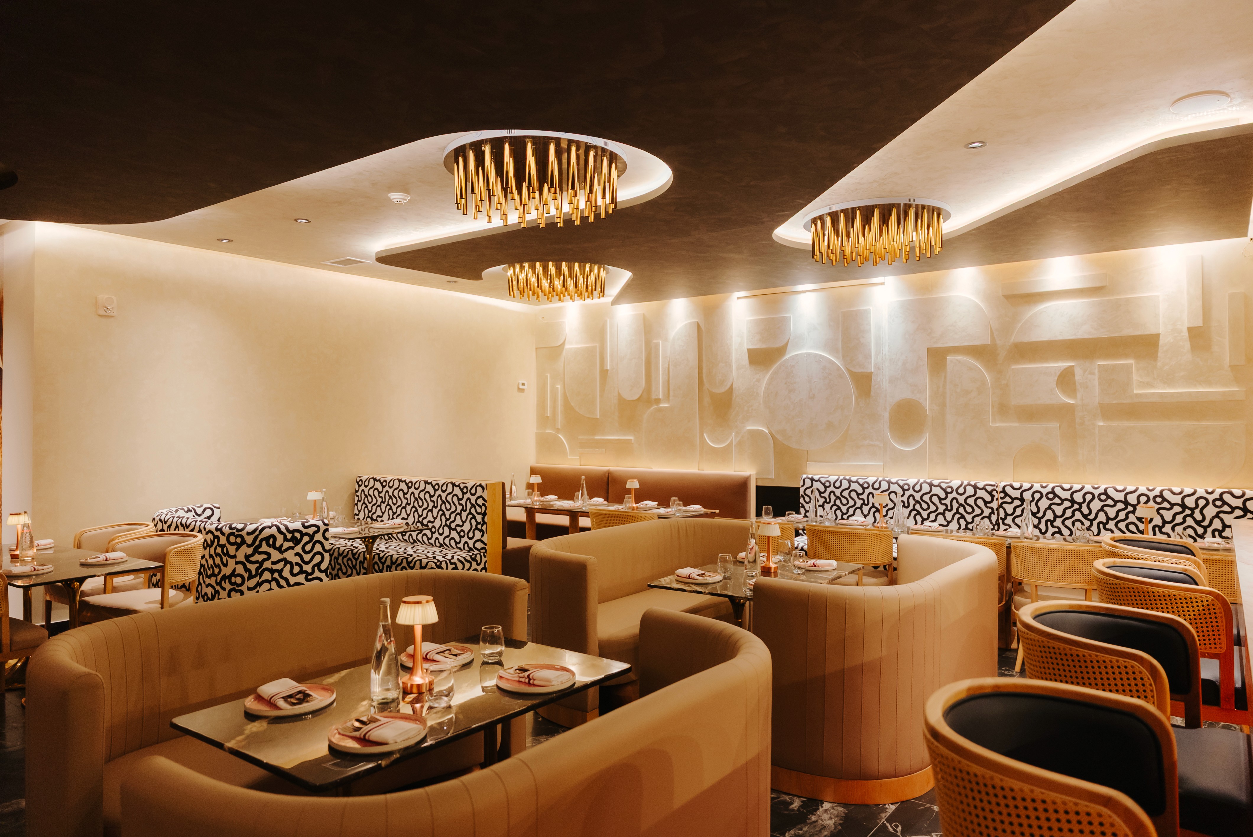 Luxury Indian fine dining restaurant interior at Dhoom Toronto featuring sculpted walls, warm lighting, plush booths, and contemporary Indian design.