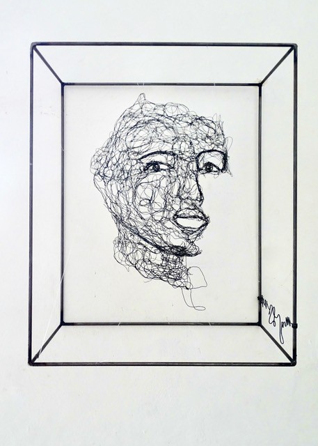 Sculpture en fil de fer représentant le visage d'une femme dans un cadre en fil de fer, vue détaillée de face