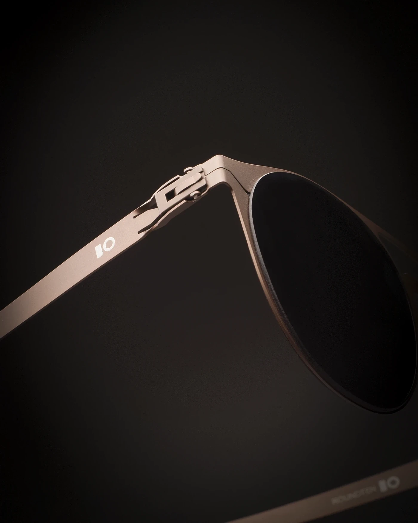 Close-up of a bronze Roundten frame with a dark lens on a dark background, packaging design by Sebastian Saavedra