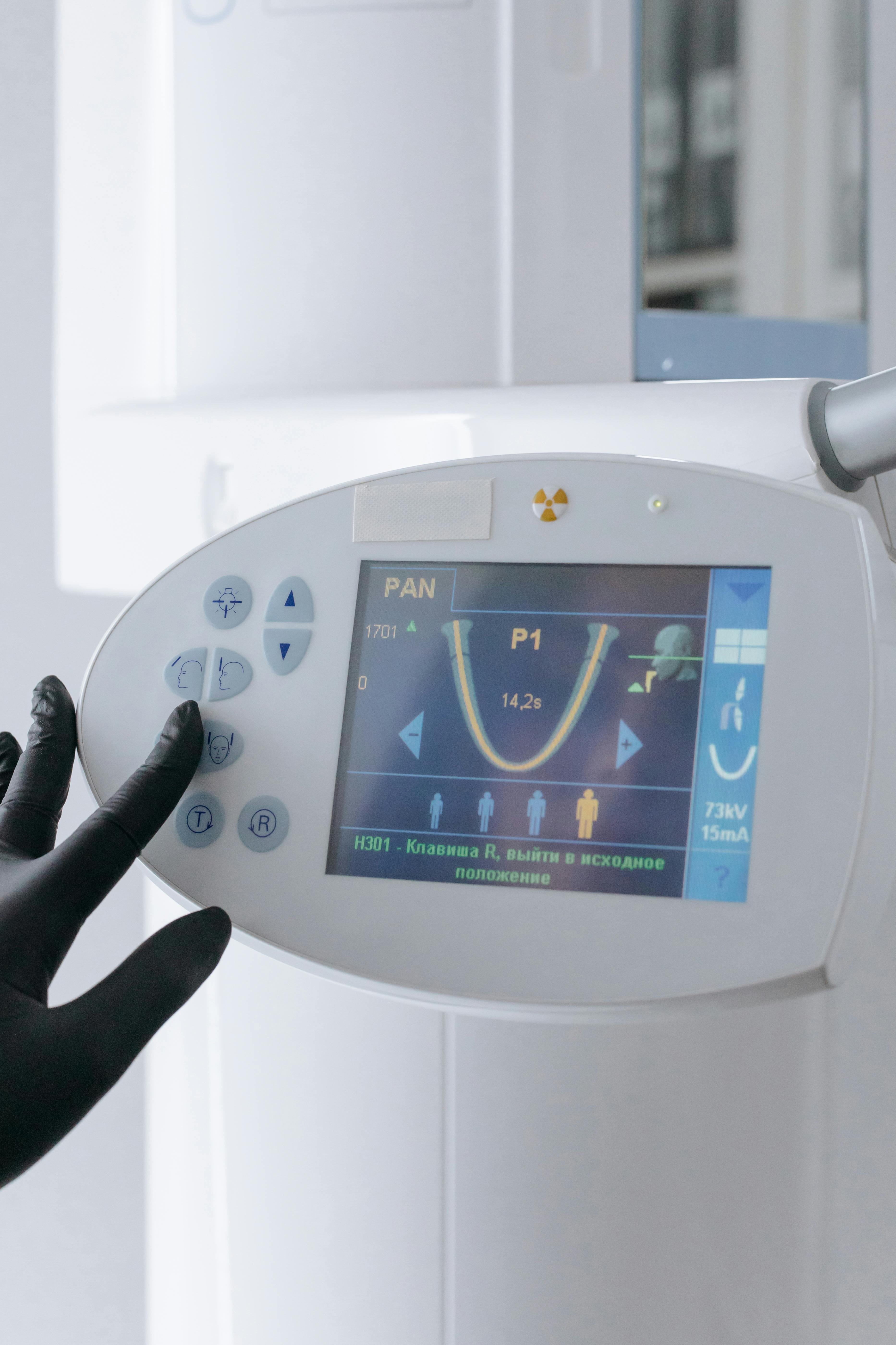 A picture of Gloved hand operating digital dental X-ray machine control panel