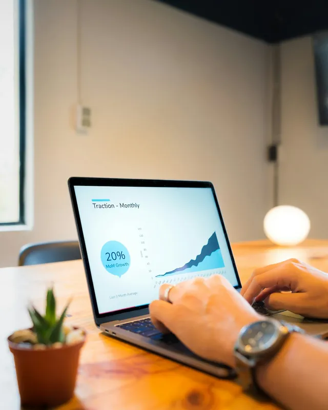 Hands typing on a laptop that shows a growth chart