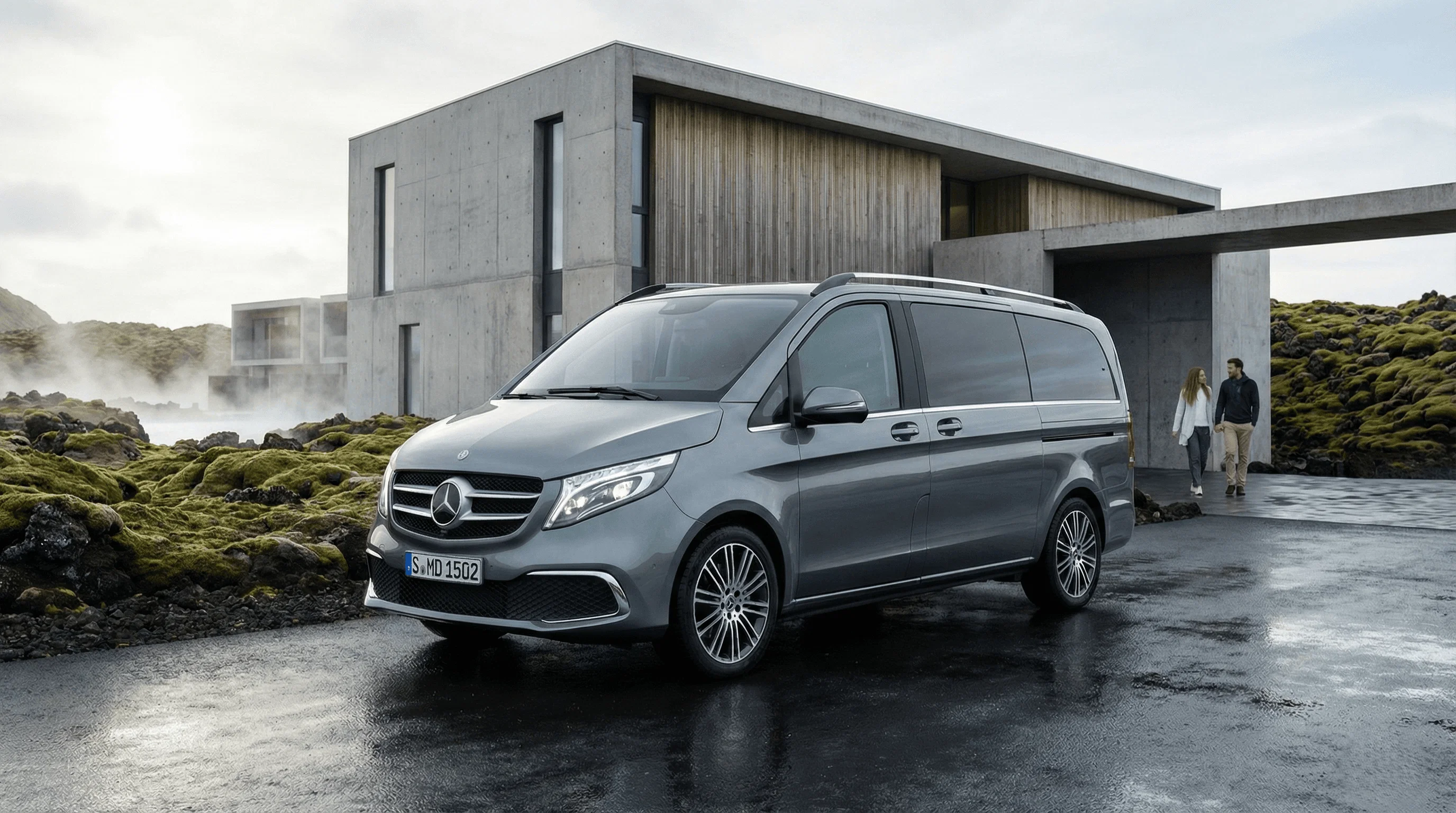 A silver Mercedes van parked on a wet driveway in front of a modern concrete building.