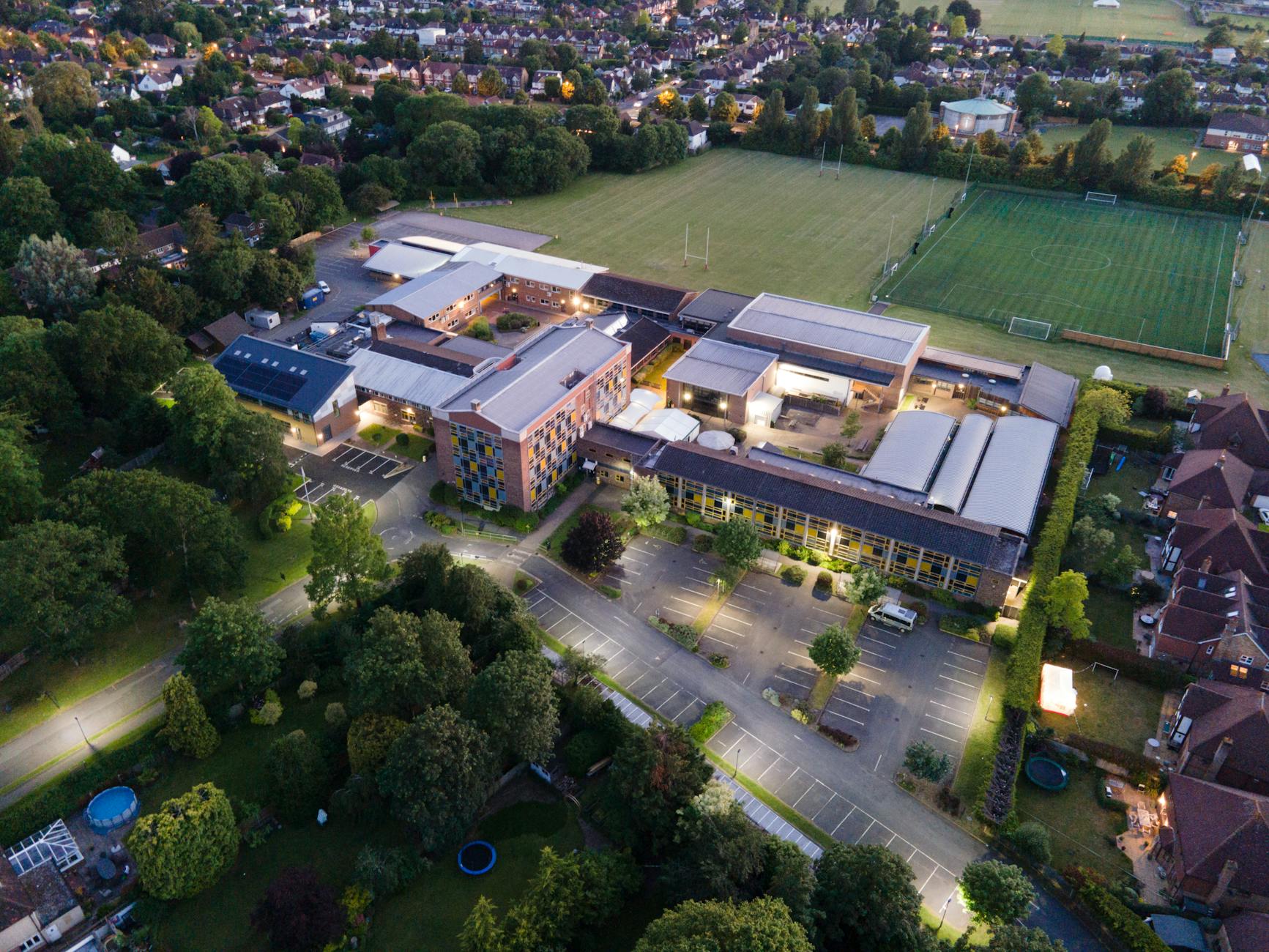 A wide-angle shot of a contemporary brick school building with large windows and a sign for an advanced learning academy.