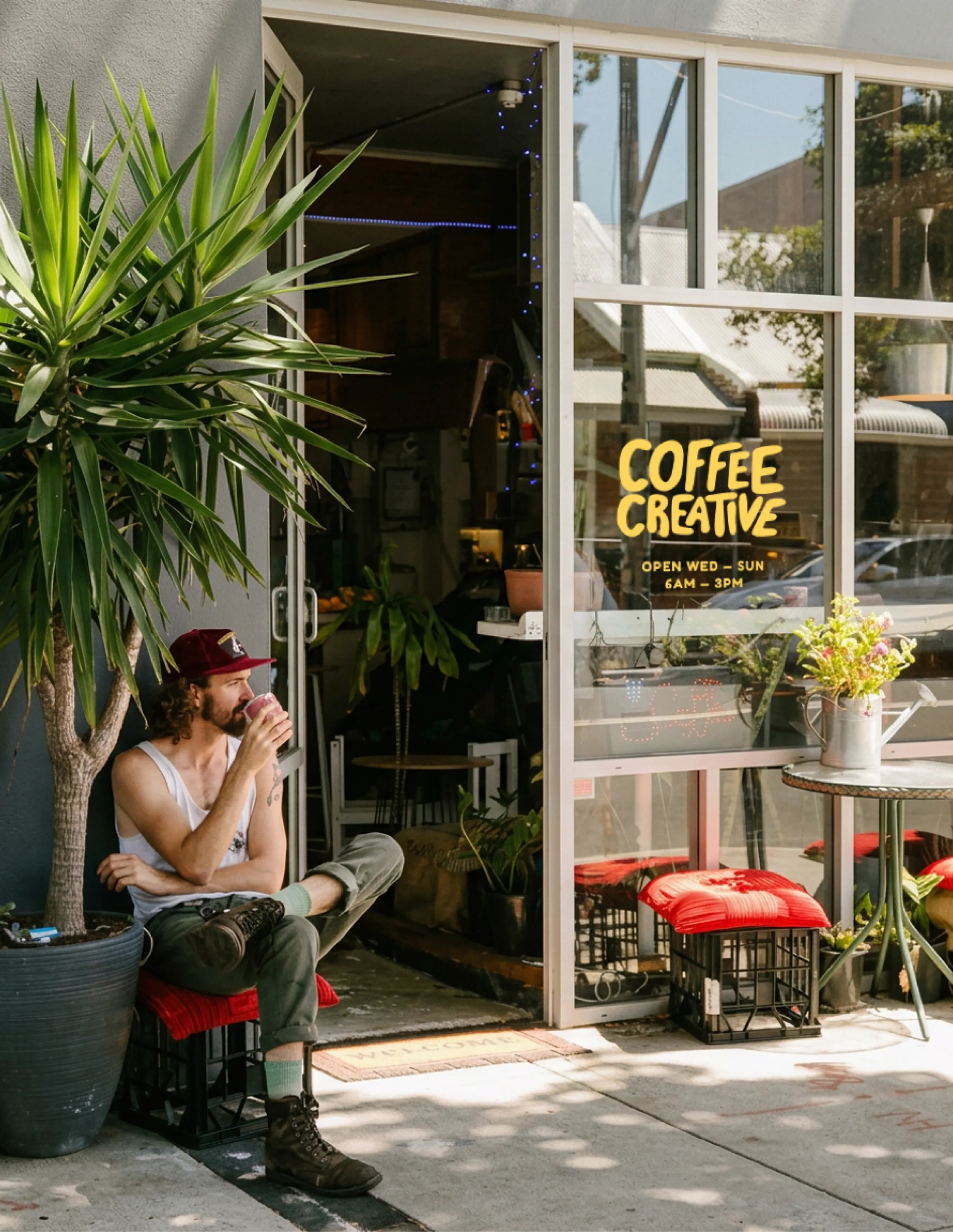 Coffee Creative shopfront signage in yellow, with a customer seated outside