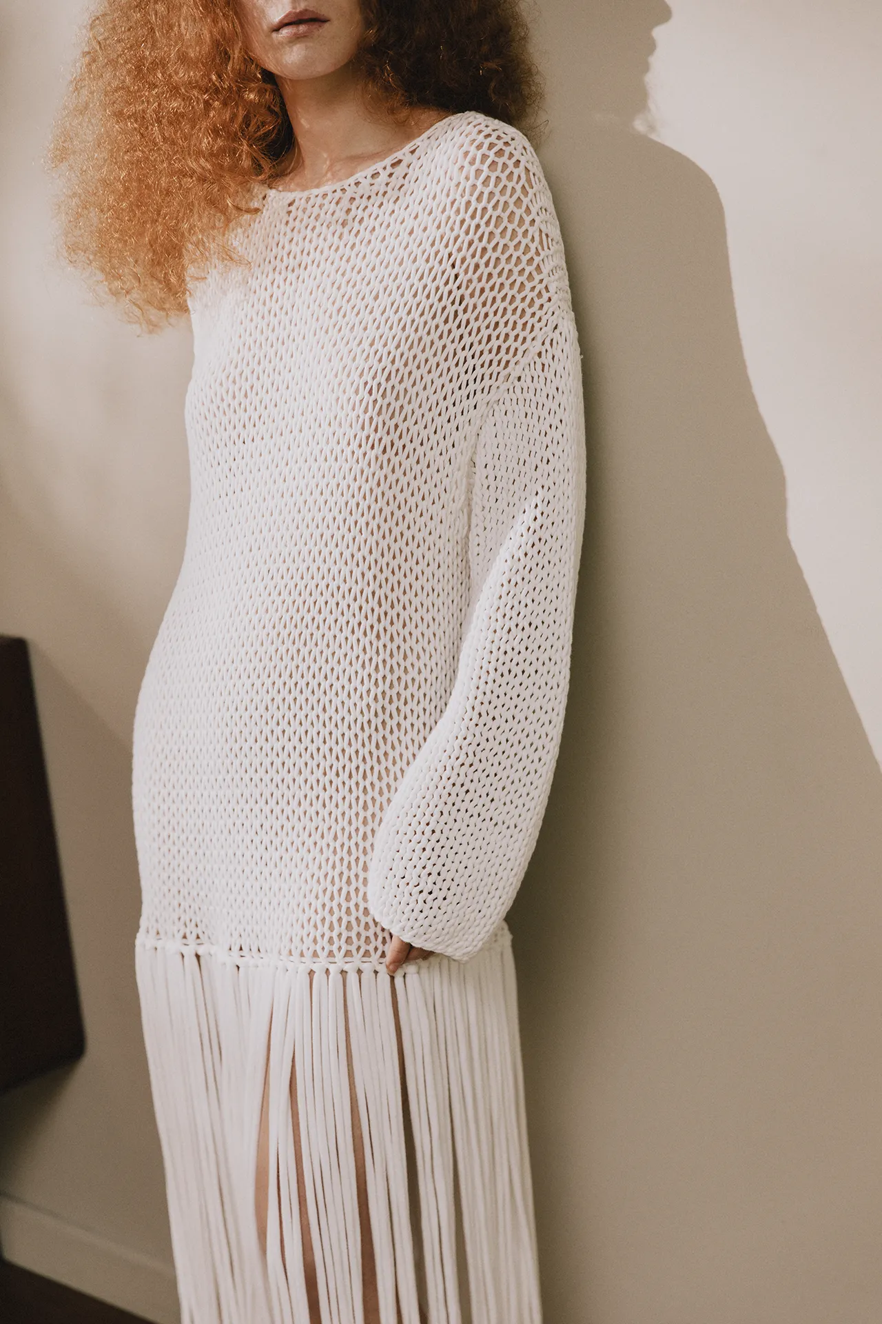 Annapurna SS26 collection white open-knit mesh tunic featuring long sleeves and fringe detailing.