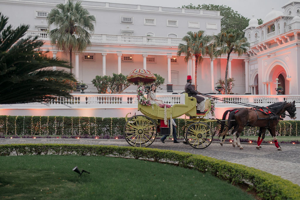 A rustic outdoor dining table set with wine glasses, cutlery, bread, and olives sits amidst lush vineyard rows, with a historic Tuscan villa in the background under a serene sky, capturing the essence of a picturesque Italian countryside landscape.