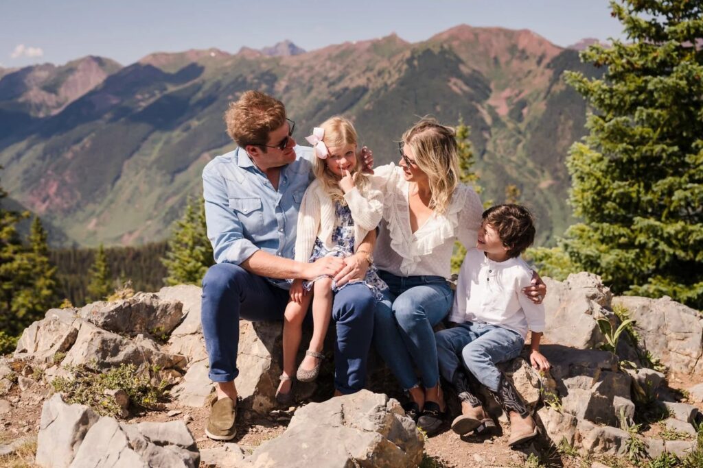 Family sitting on rocks with scenic mountain views in Aspen