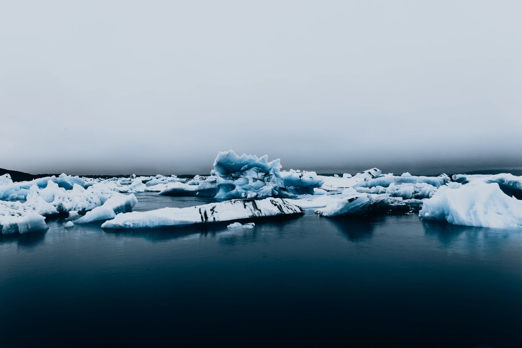 Icebergs floating in a glacial lagoon under flat grey light