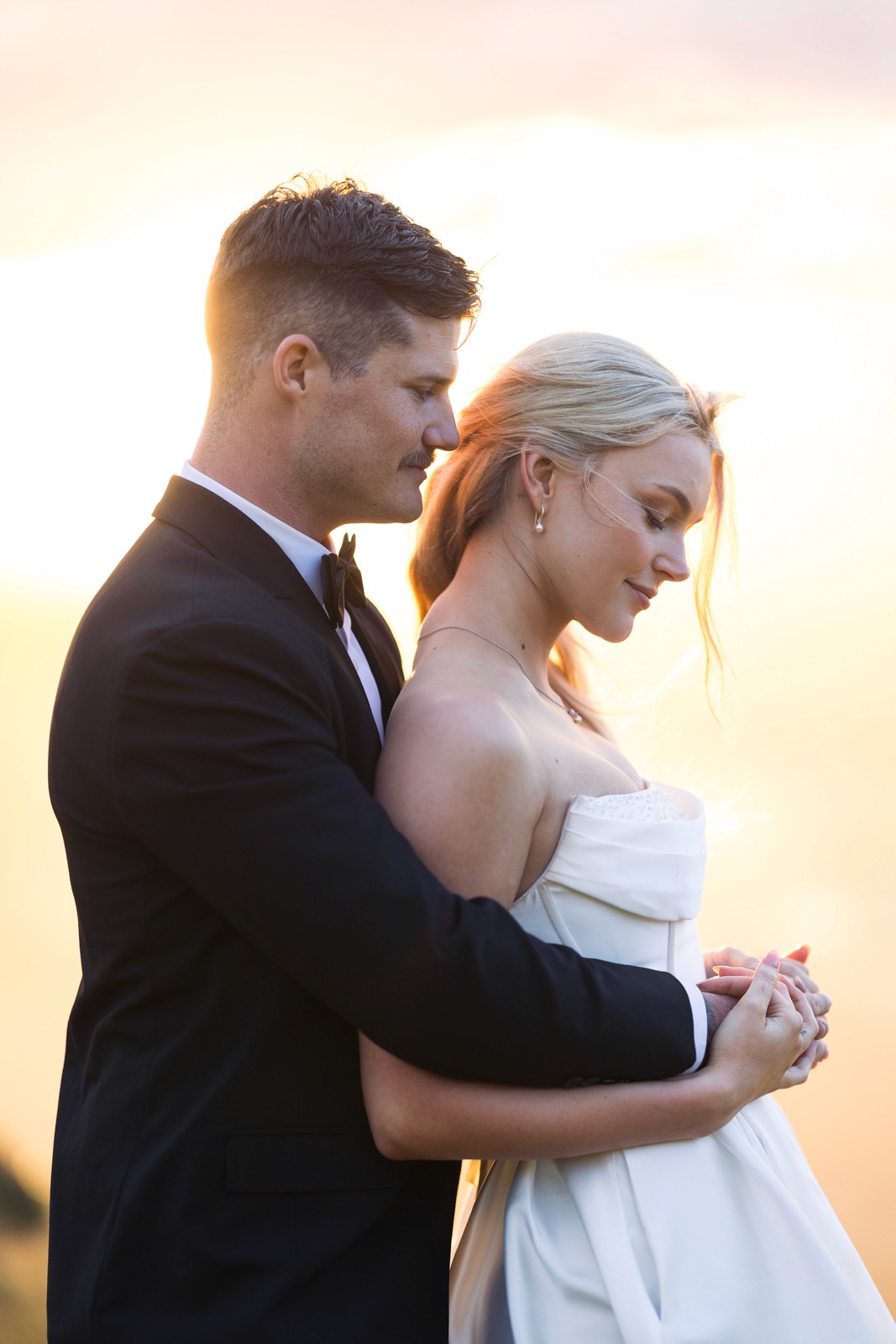 Groom hugging bride from behind