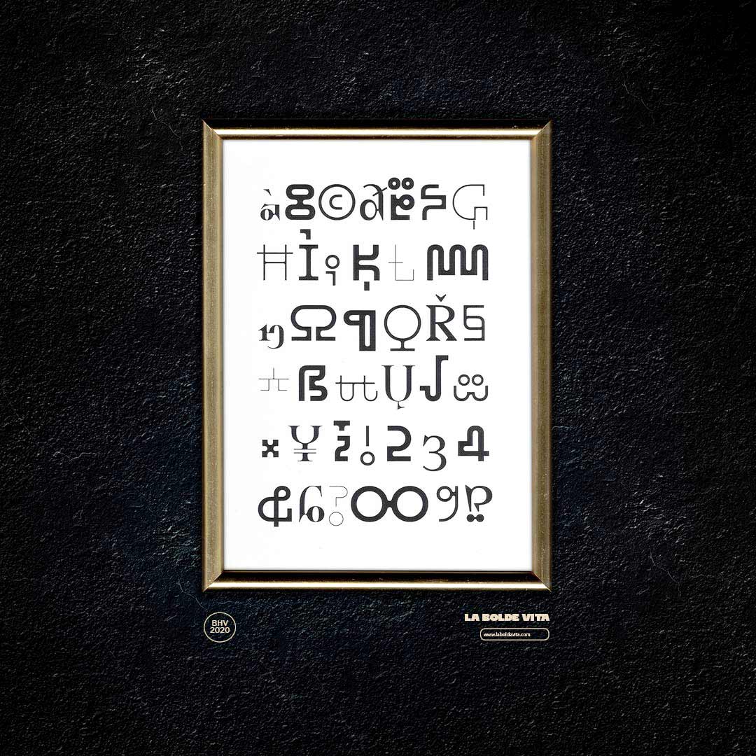 photo of a gold frame on a black wall showing alphabet-like glyphs of BHV in black on white