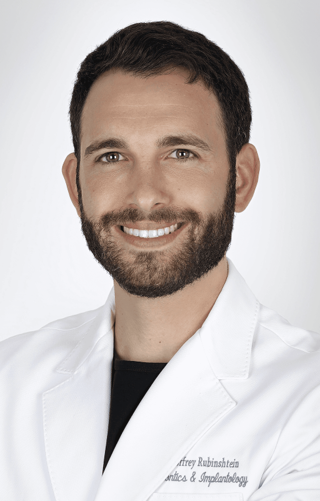 Portrait of Geoffrey Rubinshtein, Periodontist, in a white coat, smiling