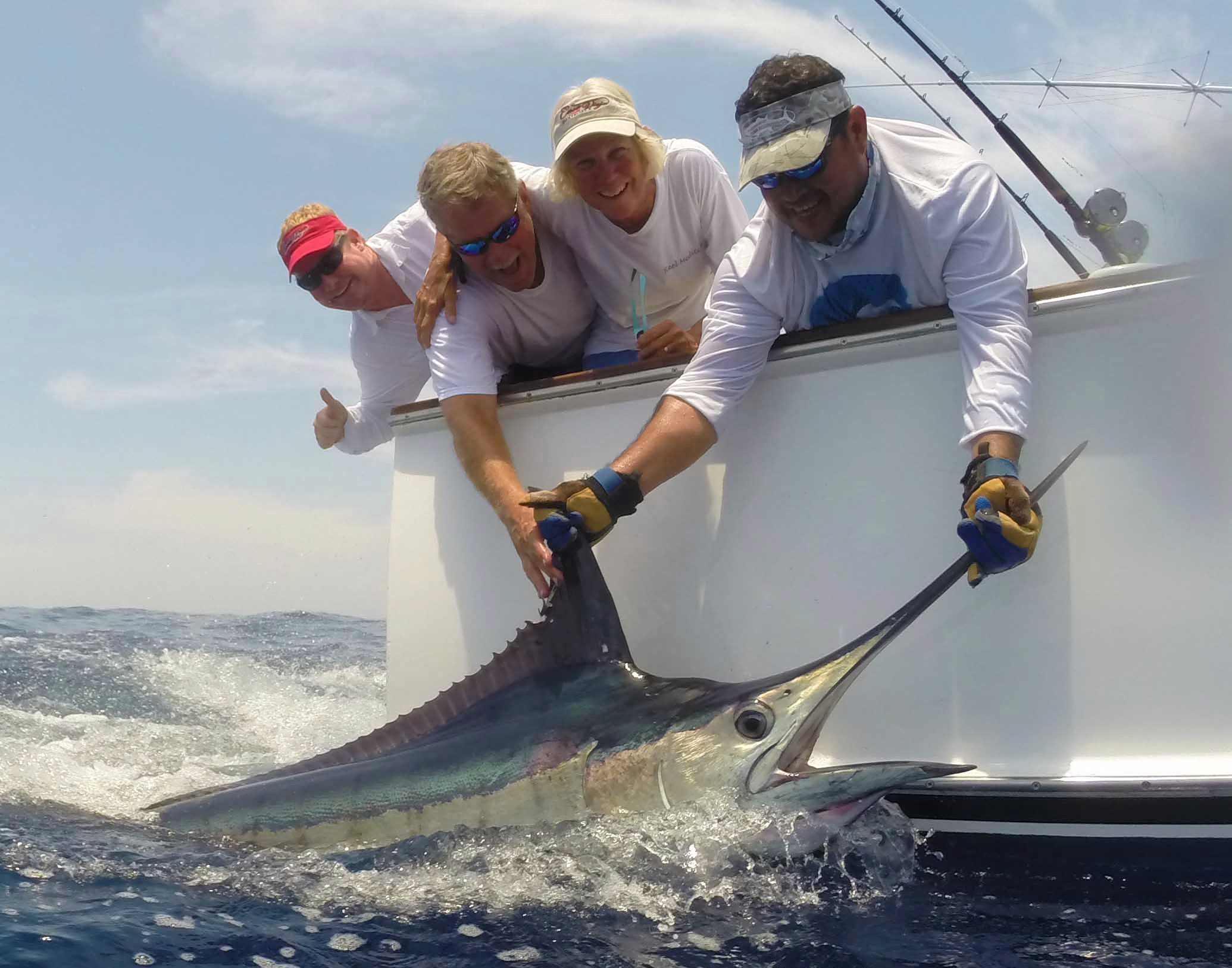 Group of anglers aboard a sportfishing boat showcasing a massive marlin catch — promotional image for the 2026 Country Fly Membership Trip to Guatemala, offering exclusive big game fishing adventures and expert-guided experiences.