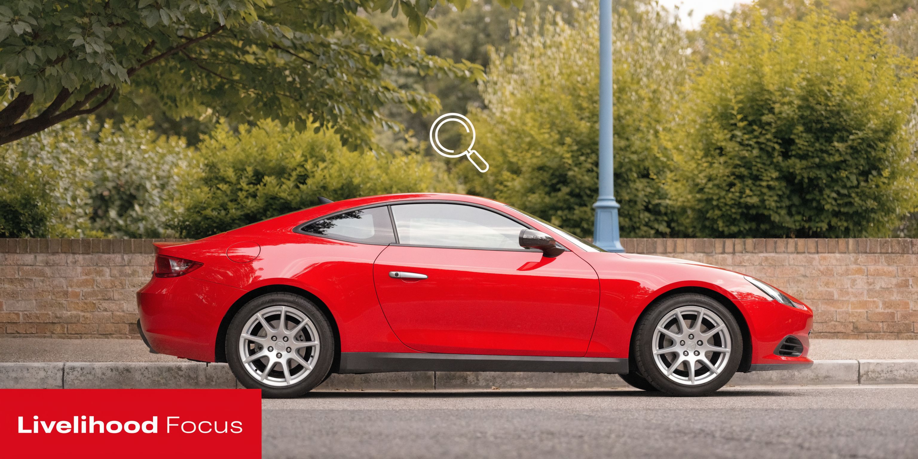A side view of a vibrant red sports car parked on a city street next to a brick wall.