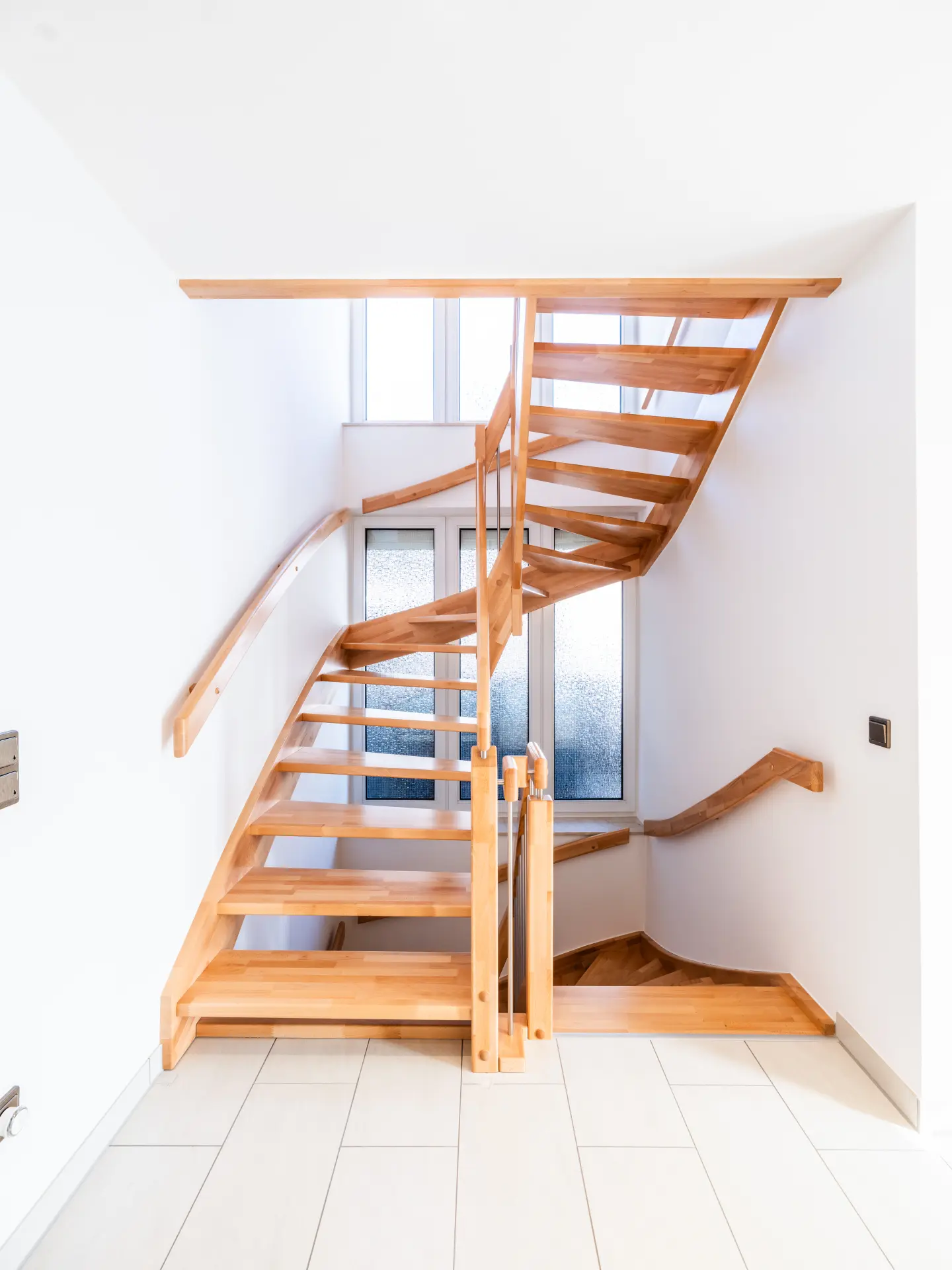 Helle Holztreppe mit Geländer als Verbindung zwischen den Etagen eines modernisierten Wohnhauses
