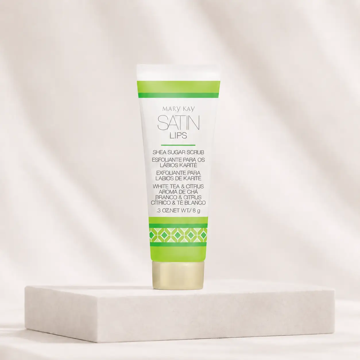 Esfoliante para os Lábios Satin Lips Karité Aroma de Chá Branco & Citrus Mary Kay, em embalagem branca e verde sobre pedestal claro